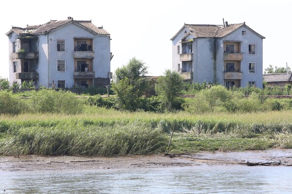 위화도의 한 건물 2층에서 하얀 메리야스를 입고 압록강을 바라보고 있는 북한인이 확연히 시야에 들어선다.