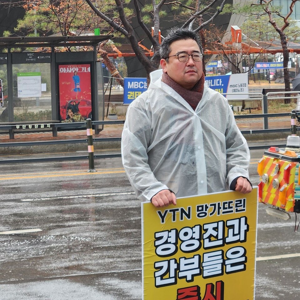 YTN방송노조의 김현우위원장이 15일 상암로 소재 YTN본사 앞 한켠에서 빗줄기가 내리는 가운데 1인 릴레이 피켓시위를 전개하고 있다.